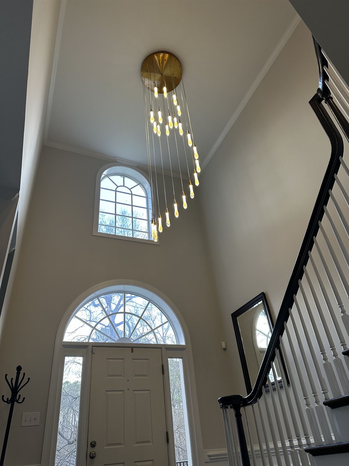 Two-story foyer with cascading teardrop pendant chandelier installed over the front entry