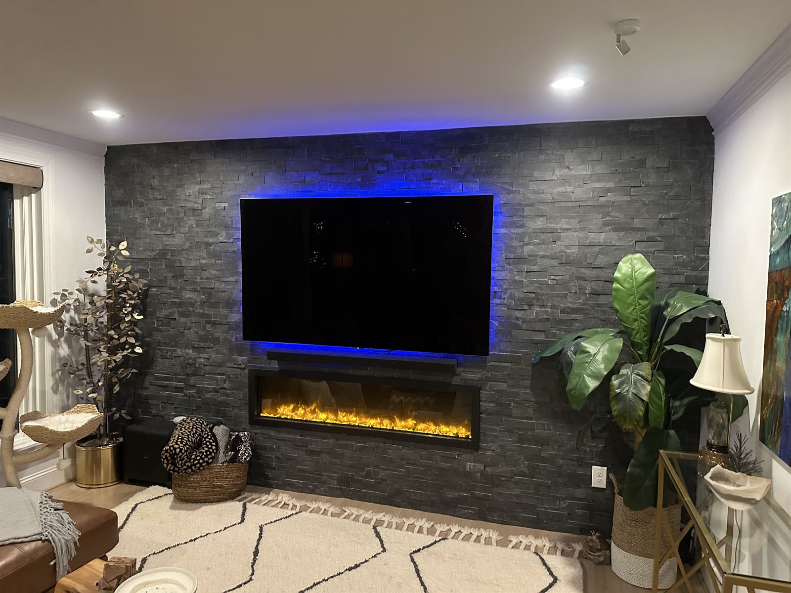 Stacked stone accent wall with recessed electric fireplace and mounted TV in a living room remodel