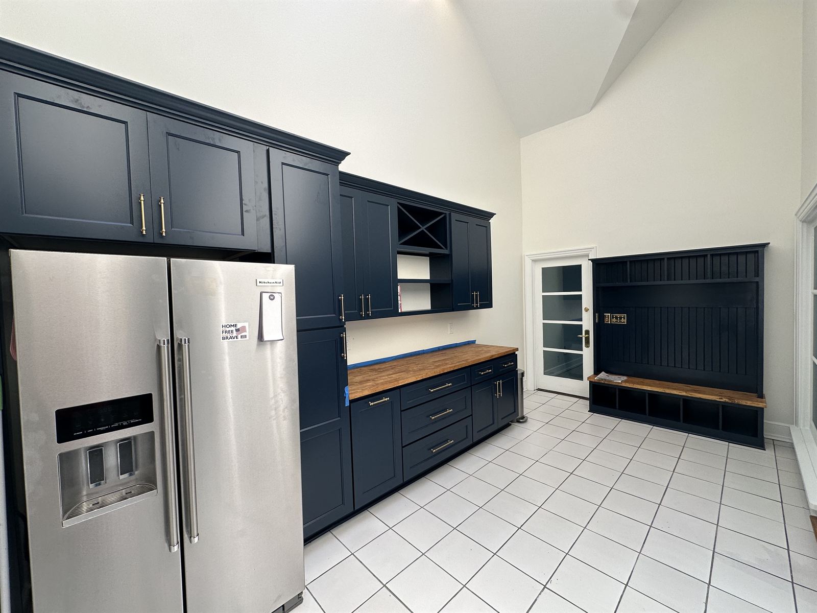 Kitchen remodel with navy blue cabinets, butcher block counter and built-in mudroom bench carpentry