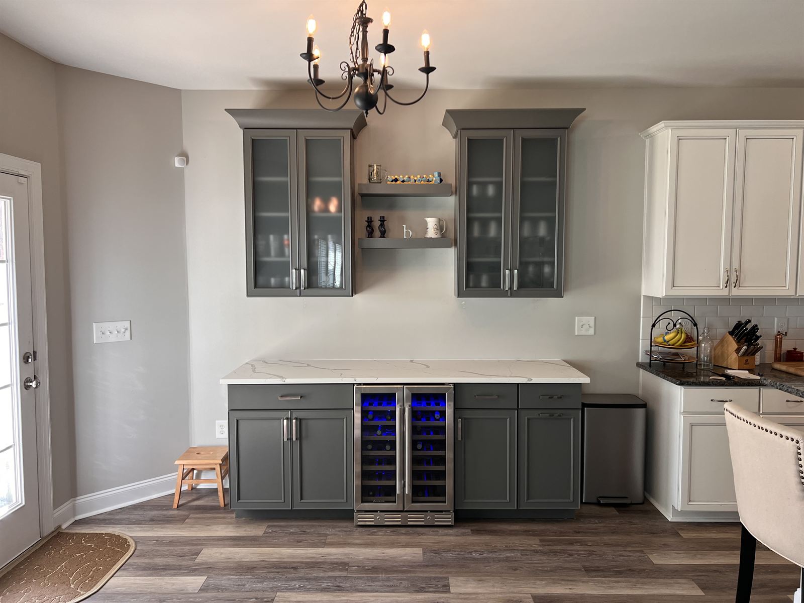 Custom wet bar with glass-front cabinets, quartz countertop, built-in wine fridge and luxury vinyl plank flooring