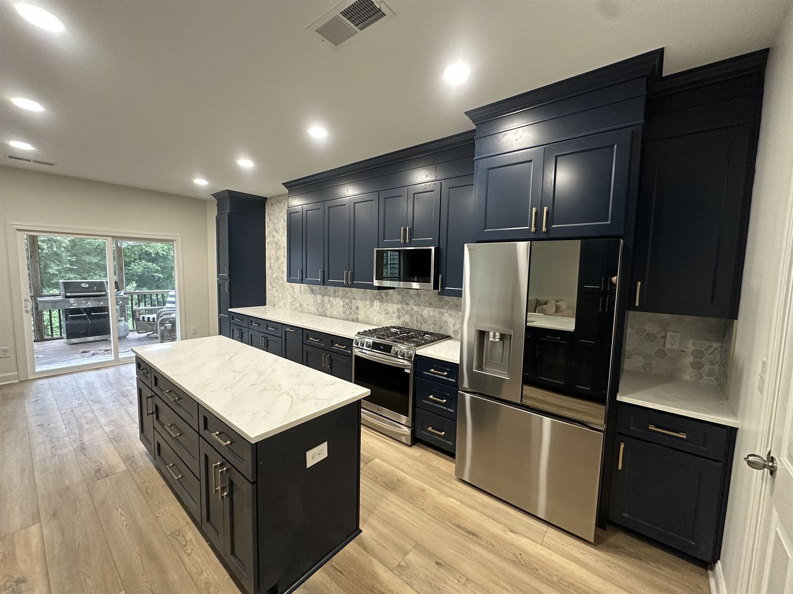 Navy blue kitchen remodel with marble-look island, hexagon tile backsplash and stainless appliances