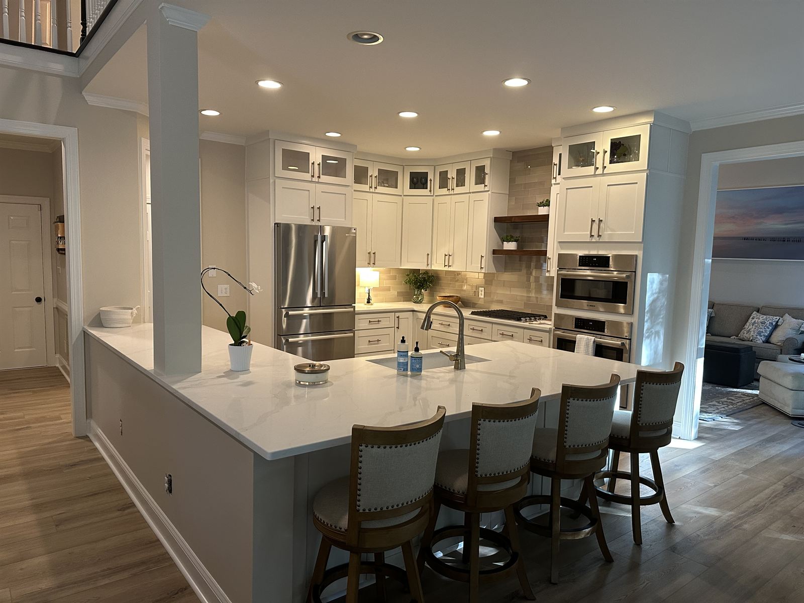 White kitchen remodel with quartz peninsula, glass-front upper cabinets and bar seating