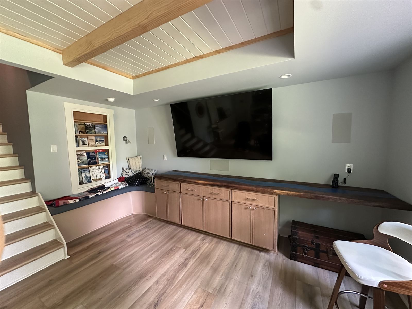 Custom carpentry in a basement remodel with built-in window seat, live-edge floating desk and media cabinets