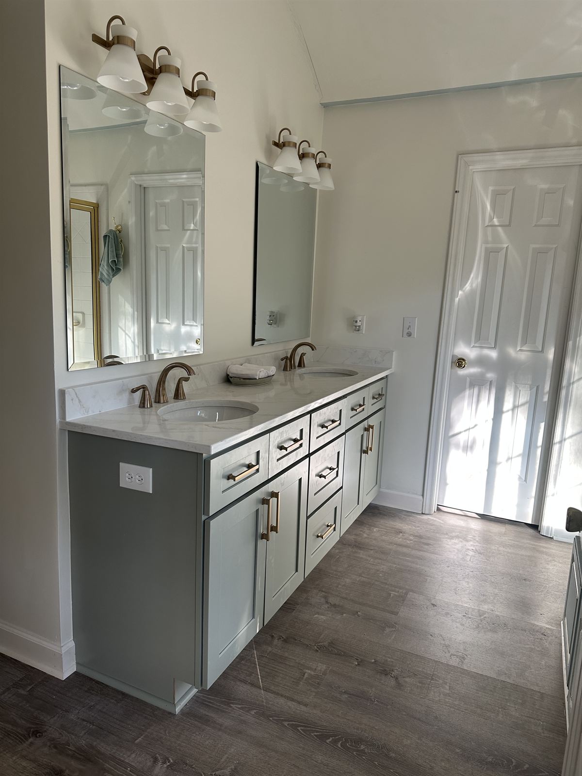 Bathroom remodel with sage green double vanity, quartz countertop, gold hardware and wood-look flooring