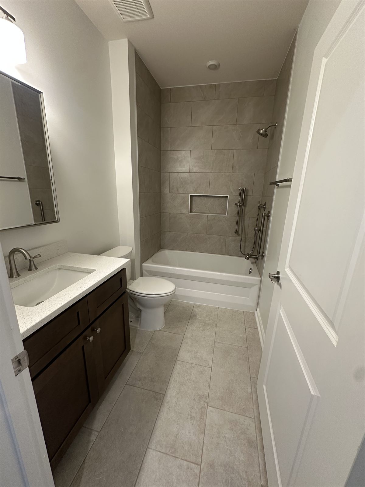 Full bathroom remodel with tiled tub and shower surround, storage niche and new tile flooring