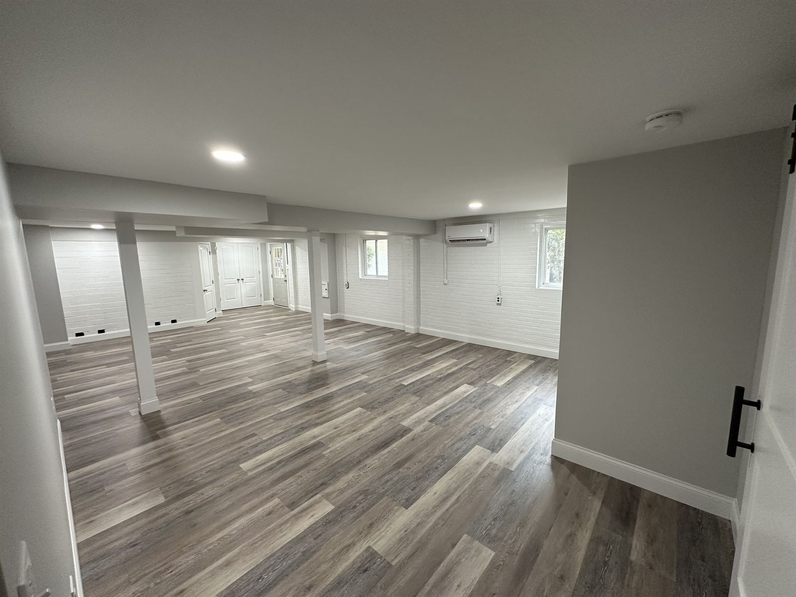Finished basement with new luxury vinyl plank flooring and painted brick walls