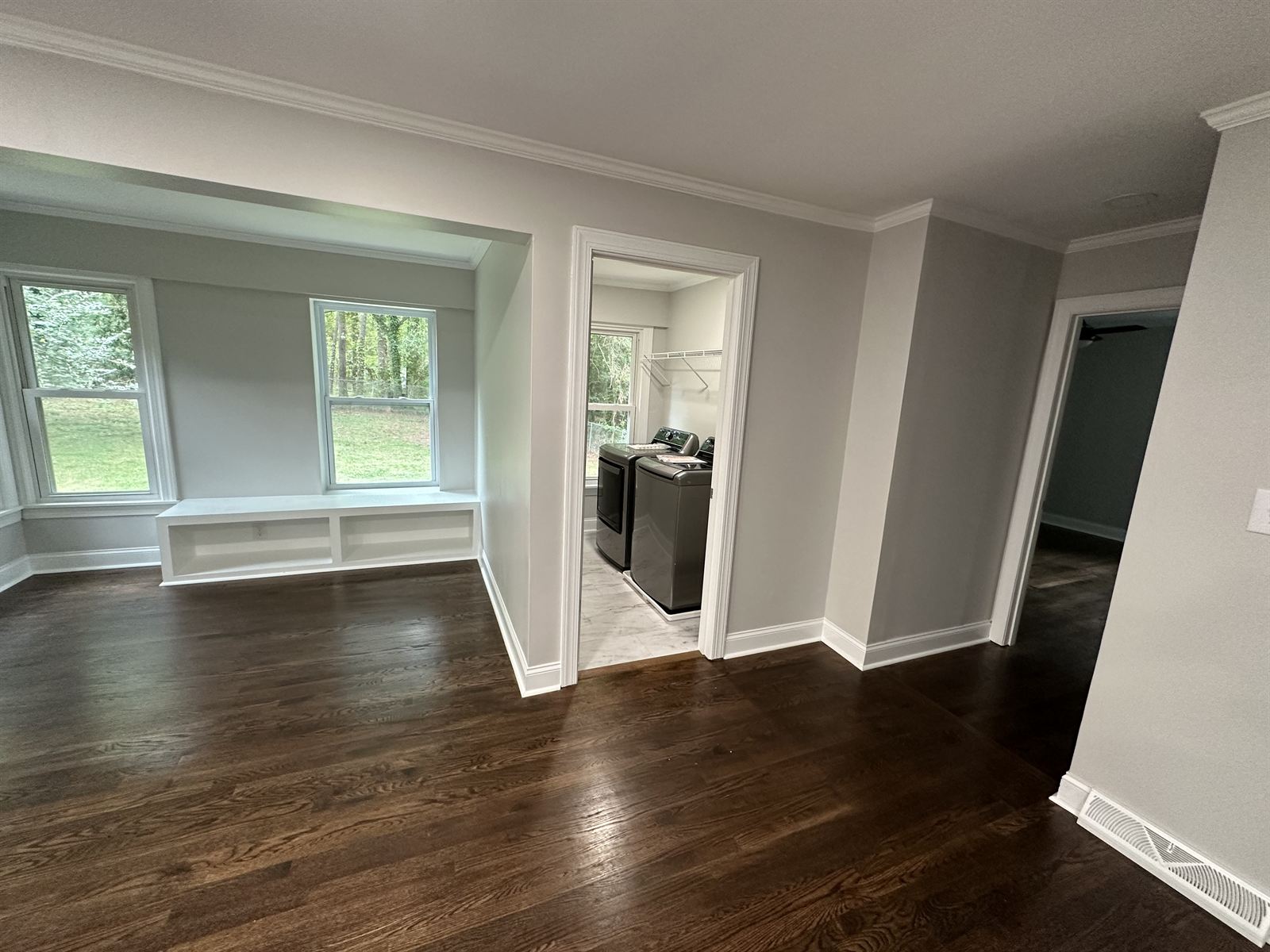 Refinished dark hardwood flooring and custom built-in window seat in a home remodel