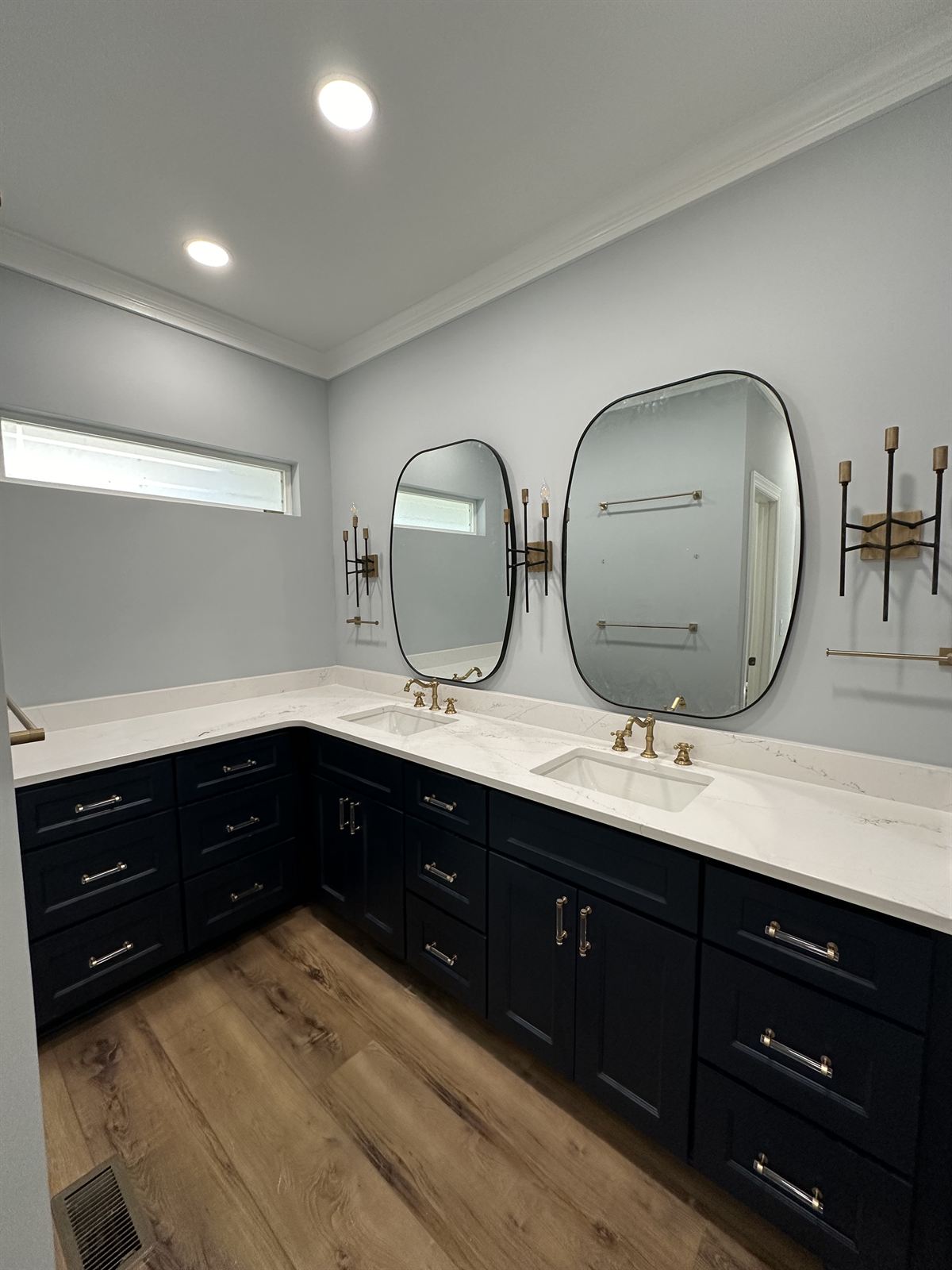 Bathroom remodel with L-shaped navy double vanity, quartz countertops and brass fixtures