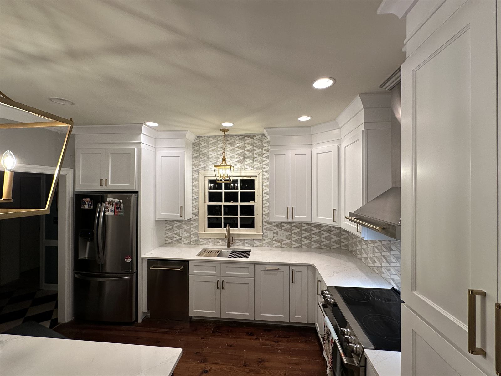 White kitchen remodel with geometric marble backsplash, lantern pendant and stainless range hood