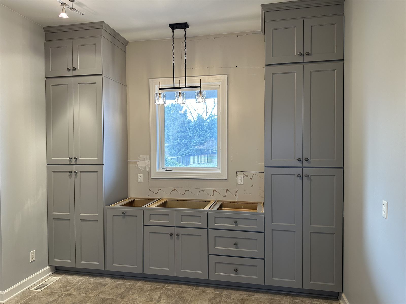 Floor-to-ceiling gray pantry cabinetry being installed during a kitchen remodel
