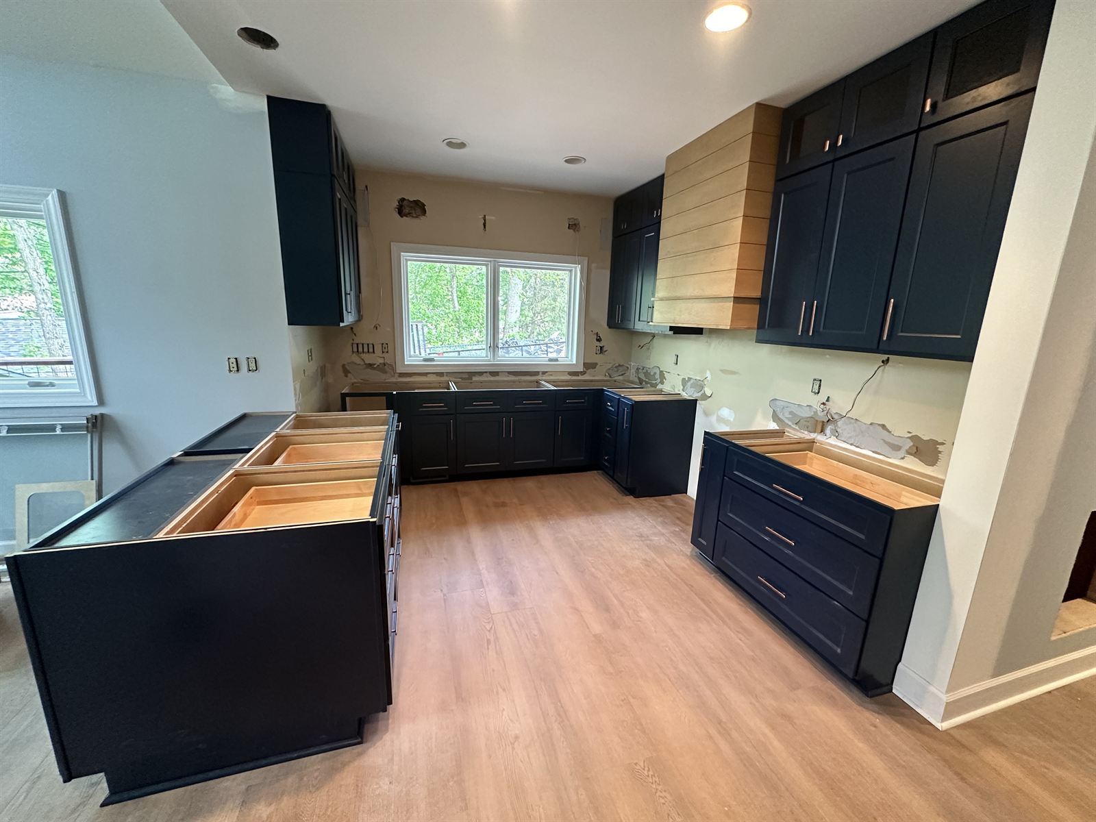 Navy kitchen remodel in progress with custom shiplap range hood carpentry and new luxury vinyl plank flooring