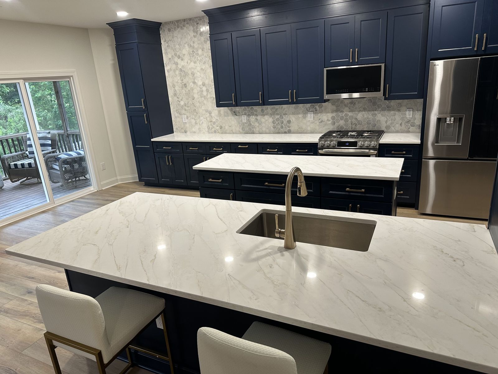 Navy blue kitchen remodel with white quartz island and hexagon tile backsplash