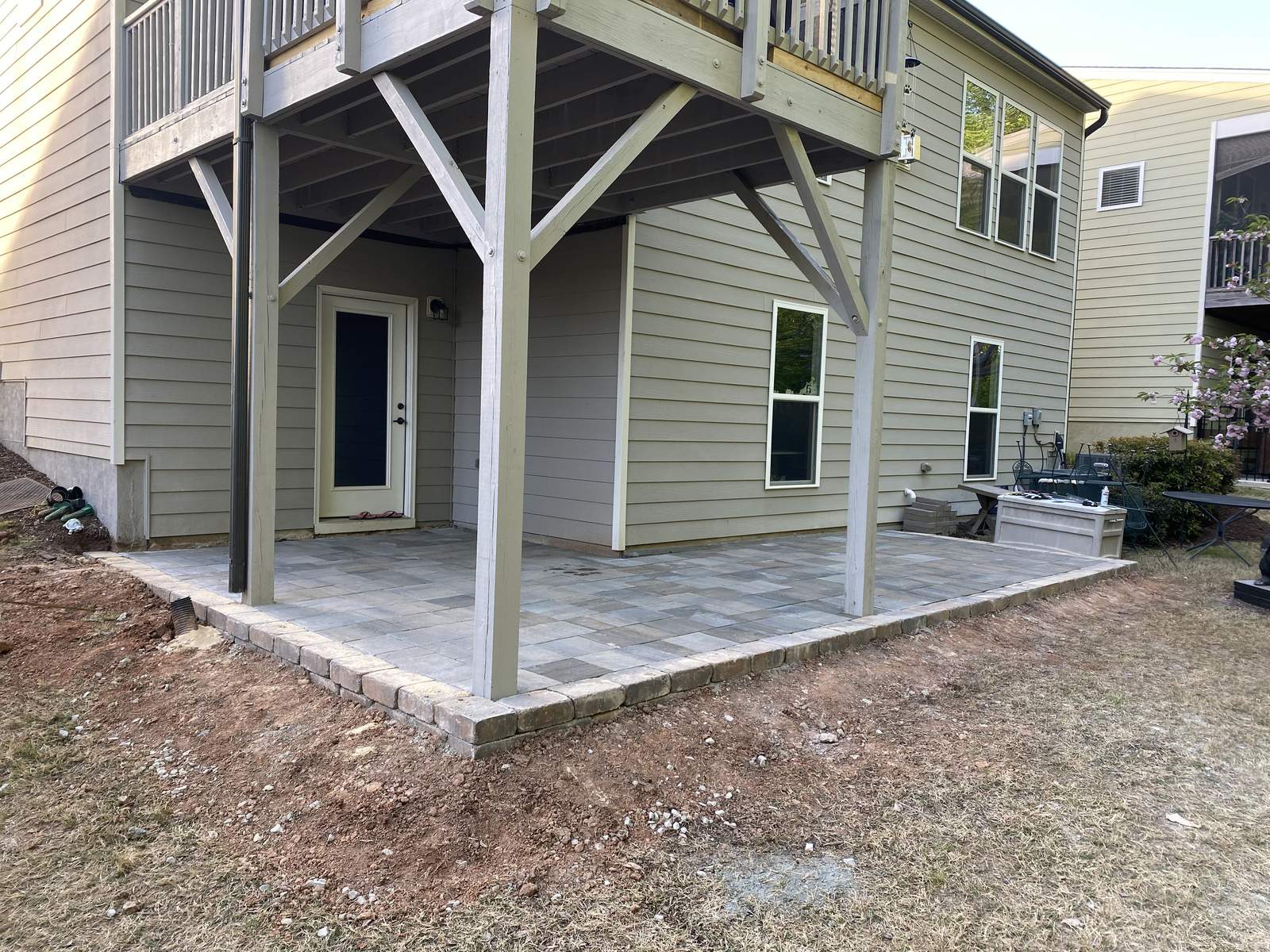 Paver patio installation under deck with retaining wall border